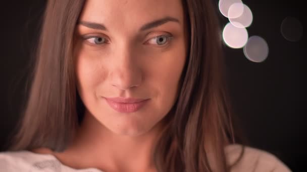 Junge Frau schaut schüchtern weg und lächelt auf blauem Hintergrund — Stockvideo