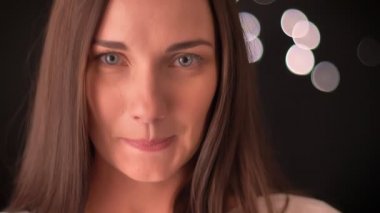 Kadın dudaklarını ısırıyor ve ikram mevsimlik-ışık arka plan üzerinde kameraya çekiyor.