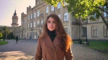 Güzel beyaz kadın üzerinde büyük Antik Bina Sonbahar zaman içinde duruyor ve kameraya, açık havada rahat seyir