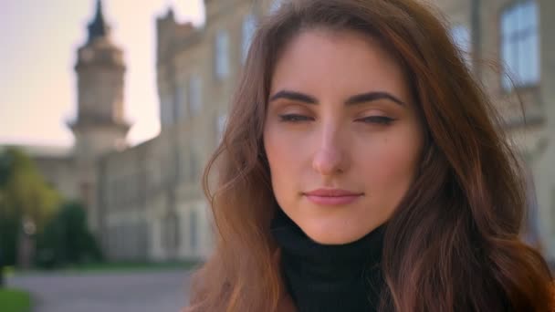 Precioso retrato de mujer caucásica de pie y mirando el frío en la cámara en el fondo de la ciudad durante el día, morena — Vídeos de Stock