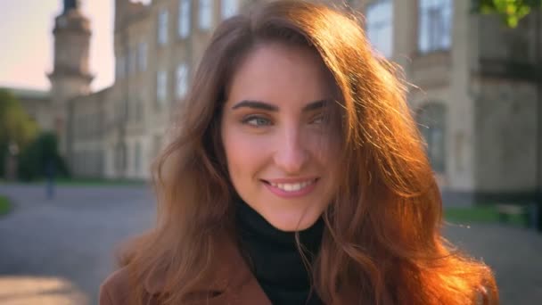 Feliz hermosa sonrisa de morena caucásica de pie sobre el antiguo edificio al aire libre, relajante y disfrutando del soleado día de otoño — Vídeos de Stock