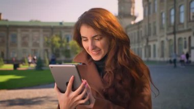 Mutlu esmer beyaz kız gülümseyerek ve yeşil ekran antik kentin binalar üzerinde güneşin altında açık havada onun Tablet kameraya gösteren
