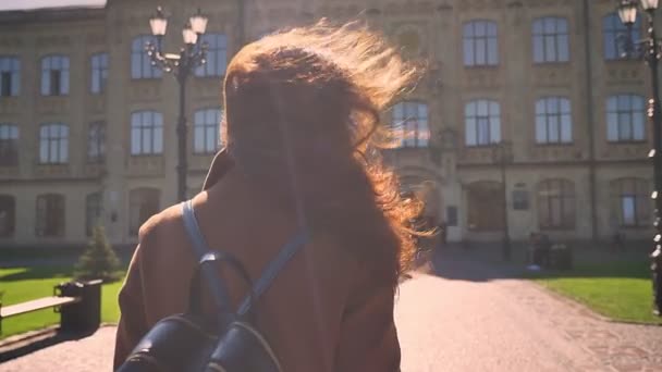 真棒高加索黑发女性是前进和笑着与她的头发在阳光下的风 对古城的建设 — 图库视频影像
