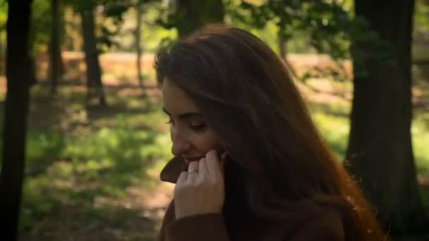 Hermosa chica morena caucásica de perfil caminando y mirando recto aislado en el parque de fondo soleado, al aire libre, movimiento — Vídeos de Stock