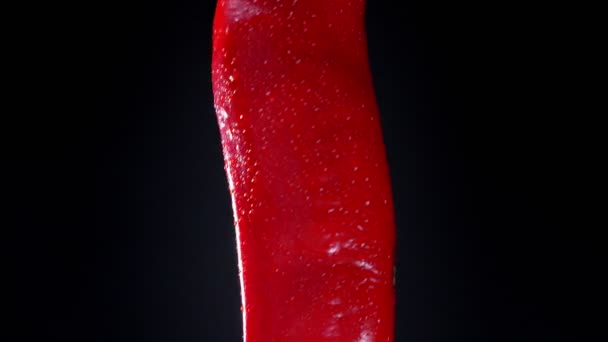 Close-up illustration from top to bottom of red chili pepper twisting around fastly on black background — Stock Video
