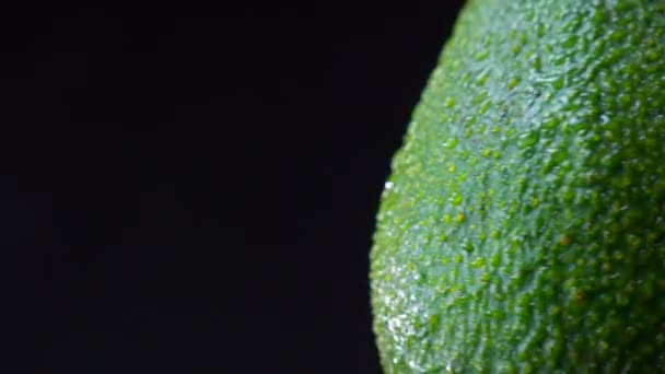 Nahaufnahme des linken Teils der grünen Avocado, der sich gegen den Uhrzeigersinn auf schwarzem Hintergrund dreht. — Stockvideo