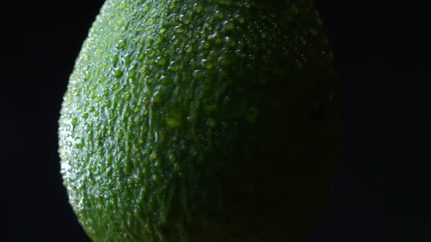 Close-up illustration of central part of green avocado spining counterclockwise on black background. — Stock Video