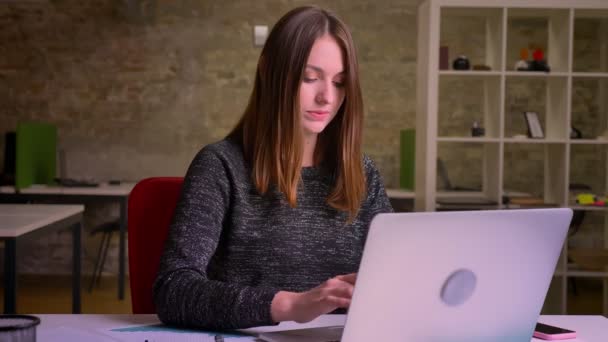 Mulher de negócios ruiva digitando no computador, assiste à câmera e coloca o dedo para cima para mostrar o semelhante — Vídeo de Stock