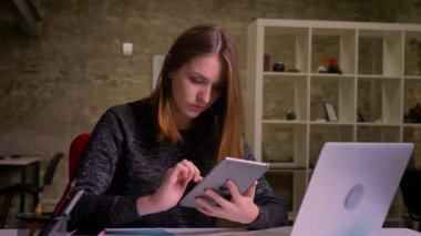 Kızıl saçlı Genç kadın tablet ve çalışma düşünceli içinde yazıhane kullanma