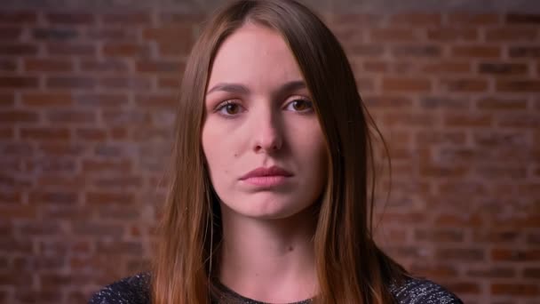 Portret zbliżenie kaukaski kobieta redheaded poważne oczy oglądać bezpośrednio do aparatu na tle bricken. — Wideo stockowe