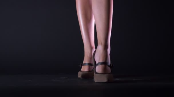 Кадри красиві ноги жінки йдуть до камери на підборах, коричневе взуття, чорний фон — стокове відео