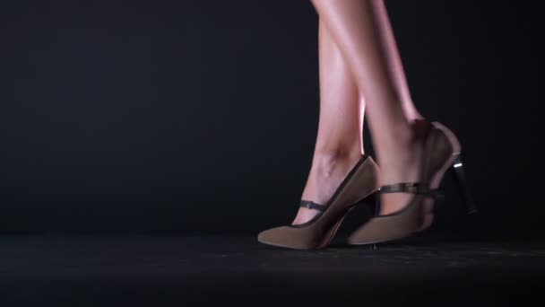 Close-up shooting of walking woman is high beautiful brown heels on black background — Stock Video