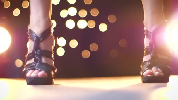 拍摄黑色的高黑色高跟鞋的腿上的妇女步行与爆发从射击, 五颜六色的光点在背景 — 图库视频影像
