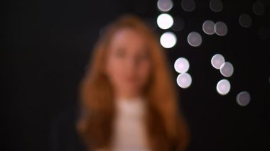 Kamera neşeyle bakmak ve üzerinden yürüme mutlu yakın çekim gülümseyen beyaz zencefil kız bulanık siyah arka plan, stüdyo, arkasında, doğal model beyaz noktalar