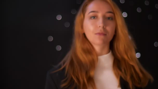 Awesome cool ingefära kaukasisk kvinna vänder i studion och ser avslappnad på kamera med ganska lugnt humör, hår i rörelse, svart bakgrund — Stockvideo