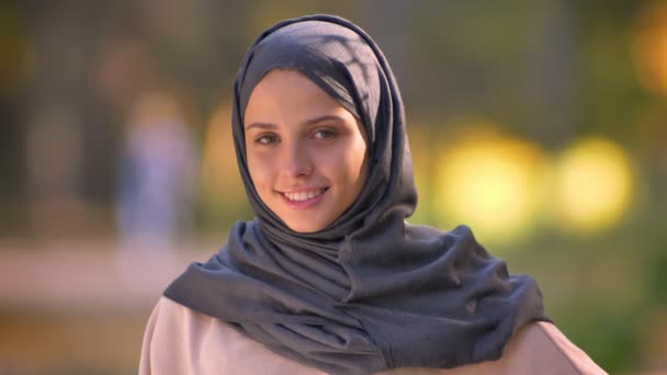 Foto close-up dari gadis muslim di jilbab menonton ke kamera dan tersenyum rendah hati . — Stok Video