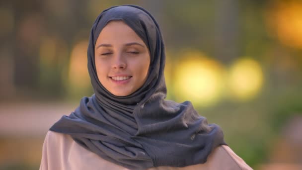 Retrato de cerca de una chica musulmana en hijab mirando a la cámara, asintiendo alegremente para mostrar su acuerdo . — Vídeos de Stock