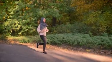 Genç Müslüman kız hijab sonbahar ormanda çalışan vurdu, dolly