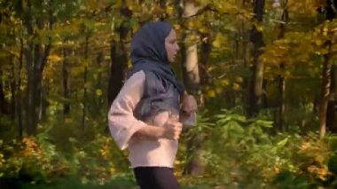 Profil, dolly atış hijab sonbahar ormanda çalışan genç Müslüman kız portre kırpılmış