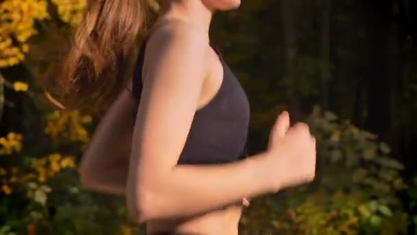 ドリー ショット、下からトップ スリム少女ジャンプ スーツで秋の公園でジョギングをする人に. — ストック動画