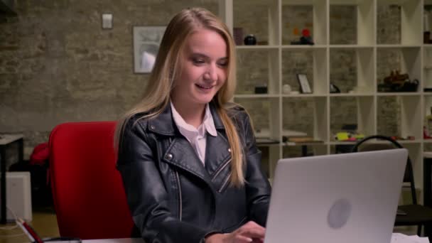 可爱的快乐金发女郎笑着看着她的笔记本电脑在办公室, 有乐趣和享受美好的一天, 在工作中, 在室内 — 图库视频影像