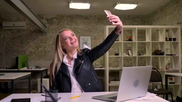 Mutlu gülümseyen beyaz Sarışın ofis çalışanı, atble ekipman çalışma ve selfies telefon, office çizim alarak yakın oturmak — Stok video