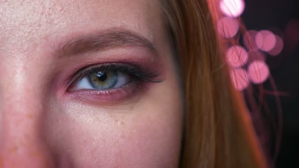 Kaukasische blond meisje, close-up groene oog make-up en eyeshadows kijken recht op de camera op zwarte achtergrond en nit knippert, natuurlijke zicht, cosmetica illustratie — Stockvideo