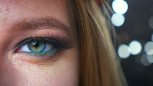 Zbliżenie modne kosmetyki na zielone oko zamknąć z kaukaski kobieta patrząc na kamery prosto, czysto naturalne spojrzenie na musujące czarne tło w pomieszczeniu — Wideo stockowe
