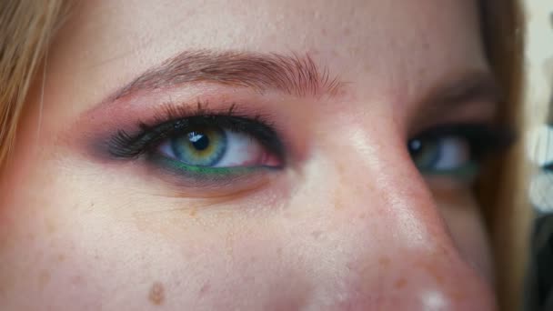 Primer plano increíble ojo verde de las mujeres caucásicas mirando a la cámara desde el perfil de disparo y parpadeo, demostración de maquillaje brillante y sombras de ojos — Vídeos de Stock