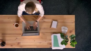 Yukarıdan aşağıya görünümü çalışma ve laptop önünde ofisindeki kahve içme raslantı giyimli kadın Dolly atış.