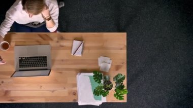 Dolly atış yukarıdan aşağıya raslantı giyimli kadın selfie-fotoğrafları yapma görünümünü Office laptop önünde smartphone kullanarak.