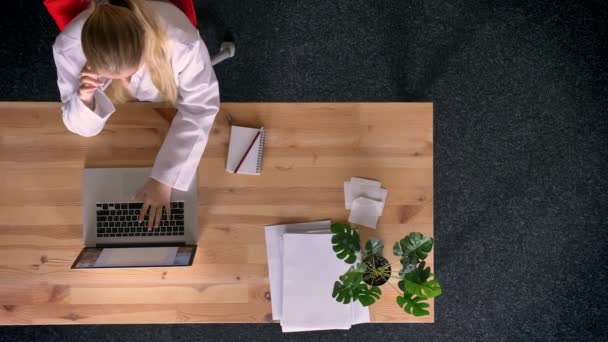 Dolly atış yukarıdan aşağıya resmen giymiş kadın cep telefonu Office laptop önünde konuşurken görünümünü — Stok video