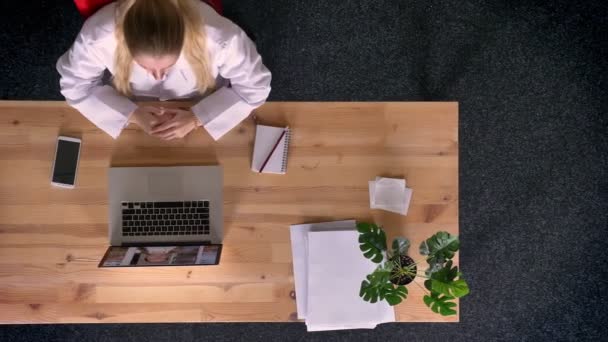 Dolly záběr shora dolů pohled formálně oblečená žena mluvila na živé překlad přes přenosný počítač v kanceláři — Stock video