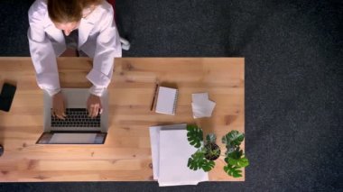 Dolly vurdu, yukarıdan aşağıya ginr kadın görünümünü dikkatle dizüstü Office ile çalışan laboratuvar önlüğü giymiş