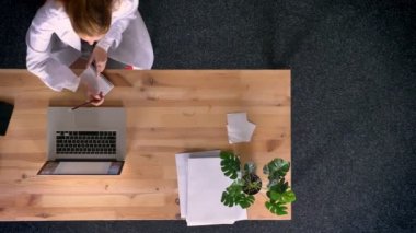 Dolly, atış çalışma ve ofiste notlar laptop önünde yapma laboratuar önlüğünü yukarıdan aşağıya zencefil kadın görünümünü giymiş