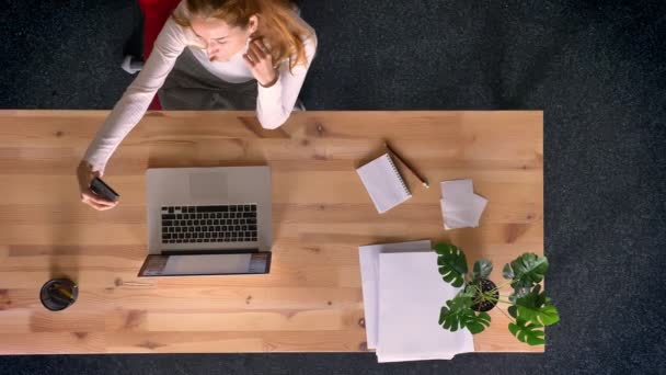 Снимок Долли, вид сверху на рыжую женщину, делающую селфи-фото со смартфона в офисе . — стоковое видео