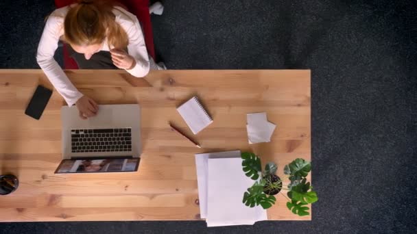 Dolly tiro, vista de cima para baixo da mulher ruiva falando em videochat usando laptop no escritório . — Vídeo de Stock