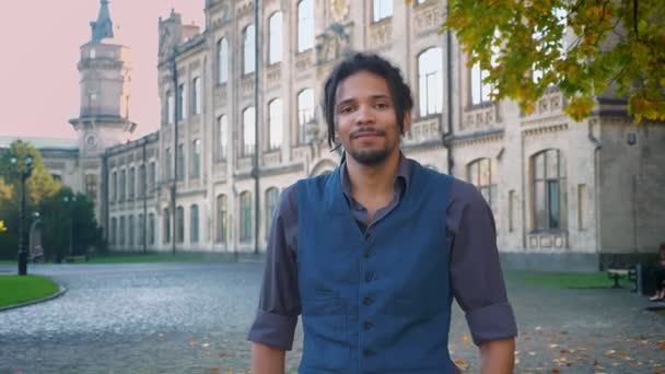 Retrato de afro-americano com dreadlocks modestamente colocando o dedo para cima para mostrar respeito e como no fundo da universidade . — Vídeo de Stock