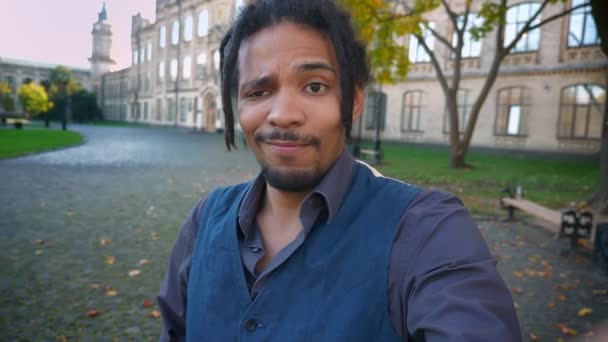 Selfie-video de atractivo estudiante afroamericano con rastas en el fondo de la universidad . — Vídeos de Stock