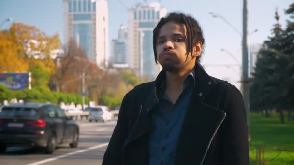 Portret van moe Afro-Amerikaanse man met dreadlocks zenuwachtig permanent in de buurt road. — Stockvideo