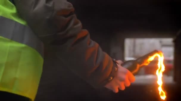 Un homme en gilet jaune met le feu à un cocktail Molotov dans une ruelle sombre. Vue arrière, émeute, concept de révolution — Video