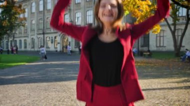 Atlama ve kollarını kadar sevinç, üniversite dışından gelen sunnny günde yükselterek çekici mutlu kız öğrenci