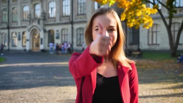 Jeune belle étudiante montre pouces levés, heureux et positif, être à l'extérieur de l'université dans une journée ensoleillée — Video