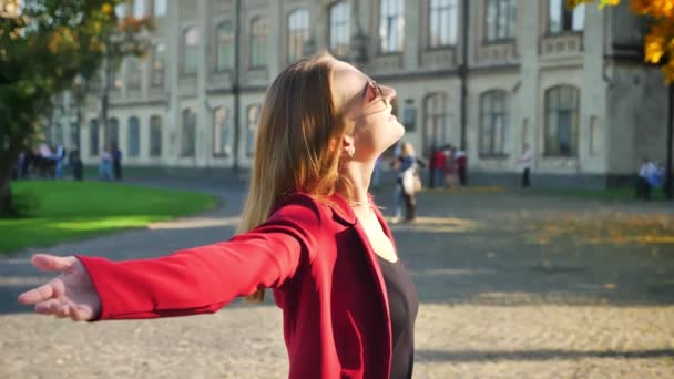 Young atrractive female, student is relaxed and calm, perceiving the nature outside the university shows love sign — Stock Video