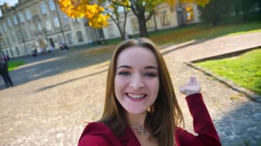 Video aramasý sahip genç güzel kız öğrenci alanı etrafında, gösterilen bir el sallayarak ve üniversitenin dışında eğlendirdi