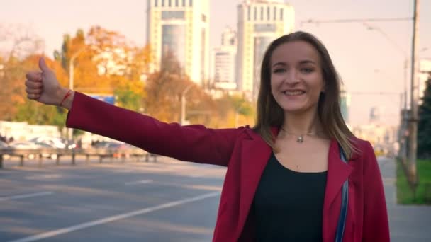 Junge attraktive Frau auf der Suche nach einem Mitfahrgelegenheit auf dem Bürgersteig, in der Stadt, scheitert, wird enttäuscht — Stockvideo