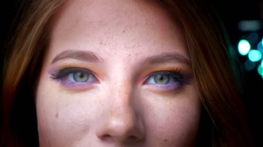 Çekici sarışın kadın mavi ışıklar arka plan üzerinde renkli göz makyaj kamerayla içine gülümseyerek yakın çekim portre.