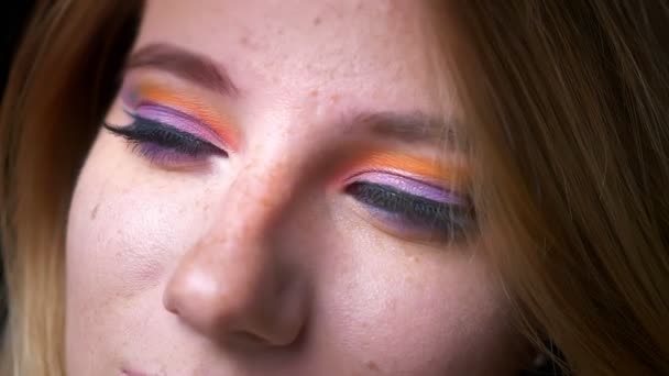 Close-up retrato de mulher loira assistindo para cima e para dentro da câmera com maquiagem colorida olho no fundo luzes azuis — Vídeo de Stock