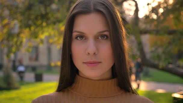 Close-up portrait of beautiful caucasian girl watching into camera with smile and shrugging humbly. — Stock Video