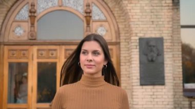 Genç ve gülümseyerek beyaz kız sonbahar park boyunca binadan atla yürüyüş portresi